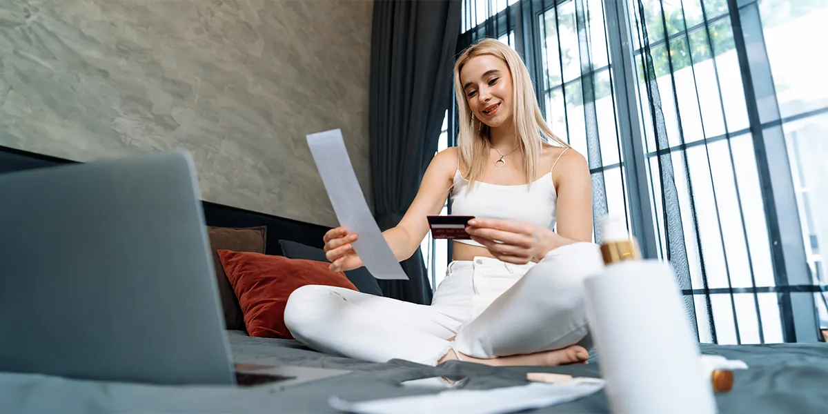 Blonde woman at home, sitting on a couch, receiving payment on her computer.