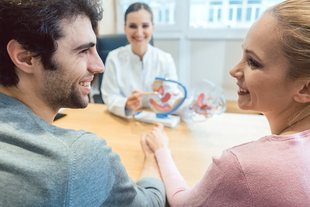 Young, smiling caucasian couple at a fertility office with a doctor.