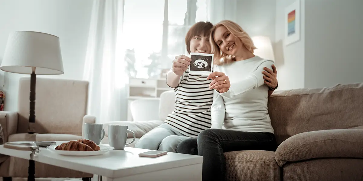 Happy lesbian couple holding a photo of their ultrasound. 