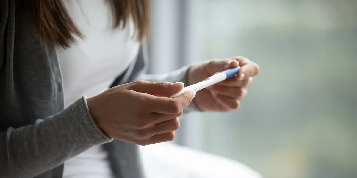 Closeup of a woman holding a positive pregnancy test. 