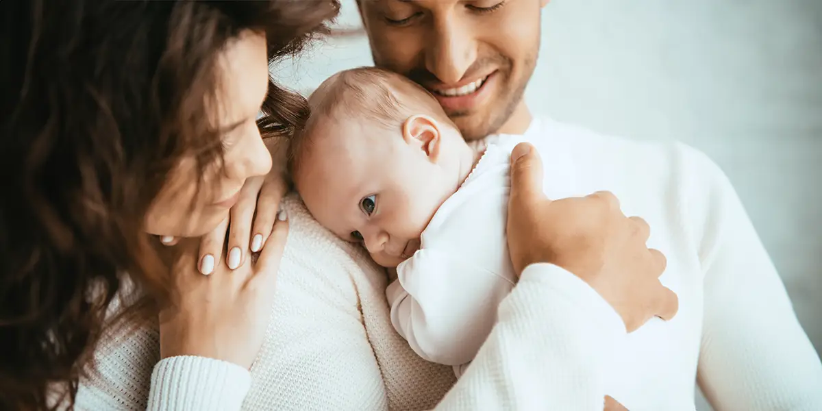 Young mixed couple holding their new baby.