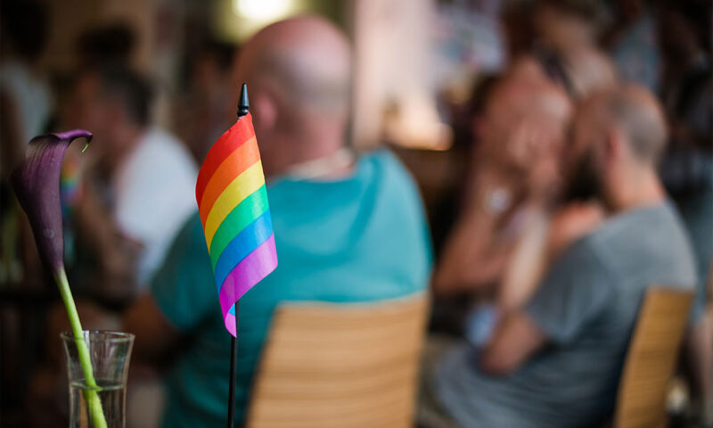 Closeup shot of gay pride flag, in front of a LGBTQ support group.