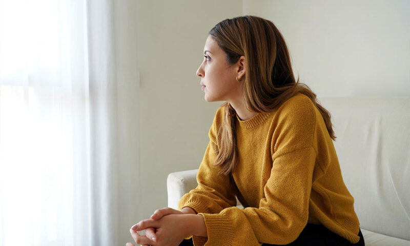 Caucasian, brunette young woman looking to the side, and feeling sad.