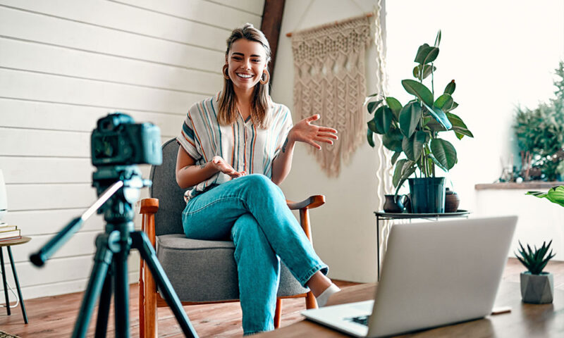 Beautiful young woman recording a video of herself with a camera. 