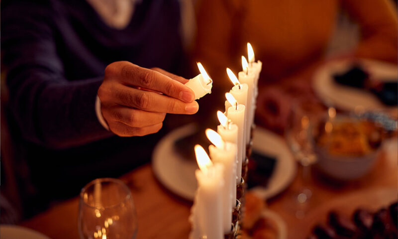 Hand lighting a menorah on Hanukkah.